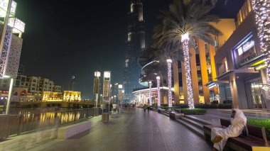 Dubai, BAE 'de çeşmenin yanında yürüyüş alanı var. İnsan yapımı gölde aydınlatılmış palmiyeler ve sokak lambaları