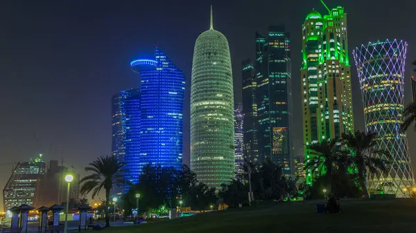 Doha 'nın yüksek katlı bölgesinde gece vardiyası, parktan görülmüş. Batı körfezinde aydınlatılmış gökdelenler ve palmiyeler