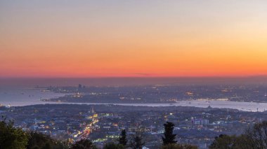 Istanbul night skyline scenery day to night transition timelapse, aerial view over Bosporus channel from Camlica hill. Blue water of Bosporus channel with ship. Traffic on roads