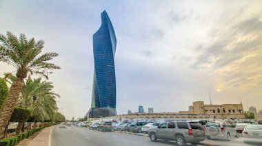 Modern twisted Tower in Kuwait City timelapse hyperlapse. Kuwait, Middle East. With palms and traffic on the road at sunset time clipart