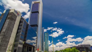 Skyscrapers timelapse hyperlapse in the Four Towers Business Area with the tallest skyscrapers in Madrid and Spain. Office district with traffic on intersection clipart