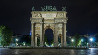 Piazza Sempione 'deki Arco della Pace (Simplon Meydanı' ndaki Barış Kemeri) ön manzara hiperhızlandırılmış gece görüşü aydınlandı. Bu neoklasik bir zafer kemeri. Arkaplanda trafik