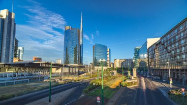 Milan skyline with modern skyscrapers in Porta Nuova business district timelapse hyperlapse in Milan, Italy, at sunset with orange light. Traffic on the road. Top view from bridge clipart