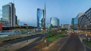Günbatımından sonra Milano 'nun Milano kentinde, Porta Nuova iş bölgesindeki modern gökdelenleri ile birlikte gece ve gündüz geçiş panoramiklerini görüyoruz. Yollarda trafik vardı. Pencerelerde ışık var. Köprüden üst görünüm