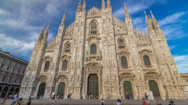 Gün batımında gölgeli Duomo Katedrali. Merdivenlerde oturan insanlarla ön manzara. Gotik katedralin tamamlanması yaklaşık altı yüzyıl sürdü. Dünyanın en büyük beşinci katedrali ve İtalya 'nın en büyüğü.