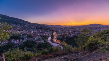 Saraybosna 'nın şehir manzarası, Saraybosna' nın en popüler panoramik noktasından gece geçiş dönemine kadar olan nehir manzarası. Sarı Kale (Zuta Tabija) yakınlarındaki yol, Vratnik