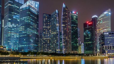 Singapore business district skyscrapers in the night time with water reflections timelapse hyperlapse. Illuminated towers with blinking lights in windows