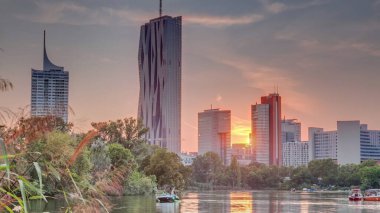 Viyana uluslararası merkez gökdelenleri üzerinde gün batımı Kaiserwasser Gölü yansıması zaman çizelgesi, Donaucity Avusturya başkenti. Bulutlu renkli gökyüzü