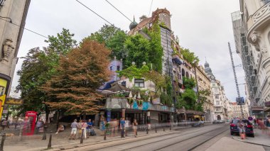 Hundertwasserhaus apartman bloğu zaman atlamalı hiperhıza, dalgalı yüzeylere, toprak ve çimlerle kaplı bir çatıya ve odaların içinden büyüyen büyük ağaçlara sahiptir. Viyana, Avusturya