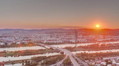 Viyana üzerinde gökdelenler, karayolu kavşağı ve Avusturya 'da nehir kenarındaki gezinti zamanı olan günbatımının hava manzarası. Tuna Kulesi 'nden akşam silueti