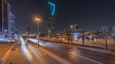 Riyad karayolu trafiğinin yer aldığı panoramik gece zaman çizelgesi, Krallık Kulesi Suudi Arabistan 'ın başkentinin en yüksek gökdeleni ve simgesi. Aydınlatılmış modern binalar canlı sahnenin etrafını sarar.