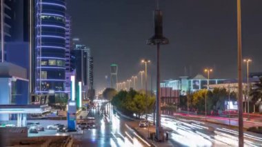 Suudi Arabistan 'ın Riyad kentindeki ikonik bükümlü gökdeleniyle King Fahd Yolu' ndaki yoğun karayolu trafiğinin hava takvimi görüntüsü. Dünyanın en yüksek sekizinci büküm kulesi. Aydınlatılmış sokaklar ve ağaçlar