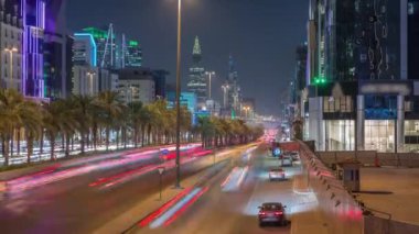 Riyad, Suudi Arabistan 'ın şehirsel gece zaman çizelgesinde aydınlık kuleler, cam gökdelenler, Kral Fahd Yolu ve yoğun trafik yer alıyor. Palmiyeler ve sokak lambaları şehrin içinden geçen ana otoyolda..