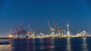 Hamburg kargo limanının gece tarifesi, Elbe Nehri 'nde konteynır terminalleri, vinçler ve kargo gemileri. Tekneler ve gemiler geçiyor ve dinamik bir deniz manzarası yaratıyorlar. Almanya