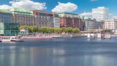 Almanya, Hamburg 'daki Binnenalster zaman ölçümüne bakın. Alster Gölü 'nün iç sularına yansıyan tarihi binalar mavi gökyüzünün altında. Gemili ve rıhtımlı manzaralı şehir manzarası