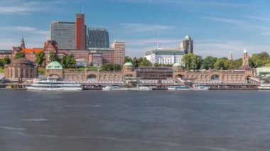 St.Pauli Piers Landungsbrucken 'de Hamburg, Almanya' da feribotlu Skyline zaman çizelgesi. İkonik saat kulesi, yat limanına yanaşan gemiler ve bulutlu mavi gökyüzünün altındaki limanın panoramik manzarası.