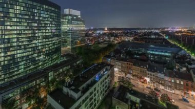Brüksel kentsel manzarasının, ofis gökdelenleriyle konut alanlarını harmanlayan gece uçuşu. Yeşil park çimenleri, tarihi çatılar ve modern mimari Belçika 'da çeşitli bir şehir manzarası oluşturur