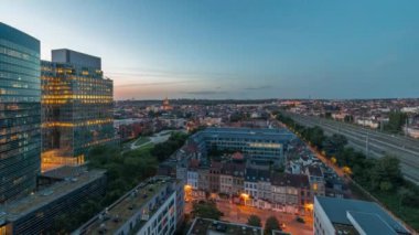 Brüksel kentsel manzarasının yerleşim alanlarıyla ofis gökdelenlerini harmanlayan hava gününden geceye geçiş zamanı. Yeşil park çimenleri, tarihi çatılar ve Belçika 'nın modern mimarisi.