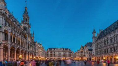 Belçika, Brüksel 'deki Grand Place Grote Markt' ın günden geceye geçiş dönemi aşırı hızlanması. Brabantine Gotik Belediye Binası, Maison Grand-Place ve tarihi şehir merkezinde gün batımından sonra turistler