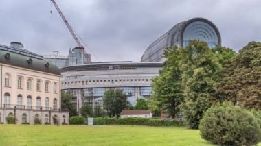 Brüksel 'deki Avrupa Mahallesi' ndeki binalar Avrupa Parlamentosu, Komisyon ve dramatik bulutlu gökyüzü altındaki kurumlarla aynı tarihe denk geliyor. Leopold Park ön planda yeşil çimenler ve ağaçlarla