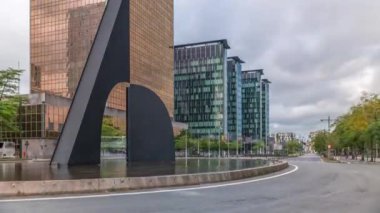 Brüksel Kuzey İstasyonu yakınlarındaki bir kavşakta bir çeşmenin zamanı. Simon Bolivar ve Roi Albert II caddelerinin kesiştiği yerde modern cam gökdelenlerle çevrili trafik akıntıları var. Belçika