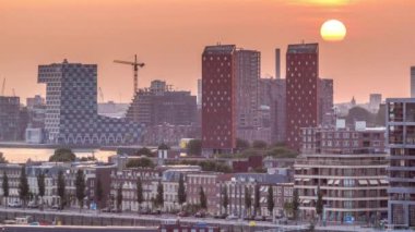 Hollanda, Rotterdam 'da gün batımında Katendrecht Yarımadası ve Maashaven Limanı' nın panoramik zaman çizelgesi. Şehir silueti, modern gökdelenler ve geleneksel Hollanda rıhtım evleri