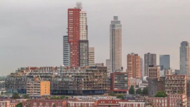 Rotterdam, Hollanda 'daki Katendrecht yarımadasının ve Maashaven limanının uçuş zamanı. Sabahları sıcak ışık, modern gökdelenler ve geleneksel Hollanda rıhtım evleri ile şehir silueti yükseliyor.