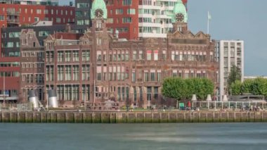 Rotterdam 'daki New York Oteli' nin tarihi görüntüsü. Eski Hollanda-Amerika Hat Karargahı. Tekneler geçerken insanlar rıhtımda dinleniyor. Limanın yanındaki ikonik mimari