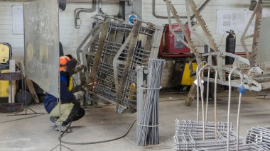 Welder working with electrode at semi-automatic arc welding in manufacture production plant timelapse. Worker in uniform and metal reinforcement