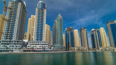 Dubai Marina Kuleleri, Birleşik Arap Emirlikleri 'ndeki gezinti güvertesi zaman aşımından suya yansıdı. Dubai Marina, Dubai 'de yer alan bir şehirdir. Mavi bulutlu gökyüzü