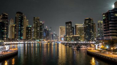 Dubai Marina Kanalı üzerinde trafik olan gezinti ve köprü gece vakti aşırı hızlanma, BAE. Palmiyeler, tekneler ve kuleler ile köprüden görüntü. Yapay kanallı bölge