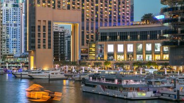 Dubai Marina rıhtımında yatları ve Dubai 'deki köprüden gece geçişine kadar alışveriş merkezi yakınlarında modern kuleleri olan Birleşik Arap Emirlikleri. Dubai Marina, Dubai 'de bir şehirdir.