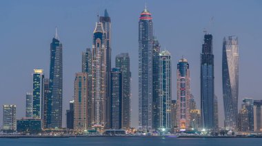 Dubai Marina ufuk çizgisi günden geceye geçiş zamanı panorama Palm Jumeirah, Dubai, BAE 'den görüldüğü gibi. Dubai 'nin bu kısmında 50 kattan fazla gökdelen var.
