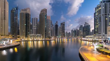 Dubai Marina Kanalı, modern kuleleri ve yatları olan liman kenti Dubai 'deki köprüden gece gündüz geçiş zamanı olan Birleşik Arap Emirlikleri' ne yansıyor. Güneş doğmadan önce etraftaki gökdelenler