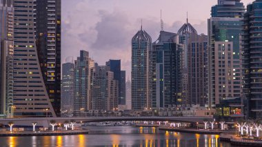 Dubai Marina Kanalı, modern kuleleri ve yatları olan liman kenti Dubai 'deki köprüden gece gündüz geçiş zamanı olan Birleşik Arap Emirlikleri' ne yansıyor. Güneş doğmadan önce etraftaki gökdelenler