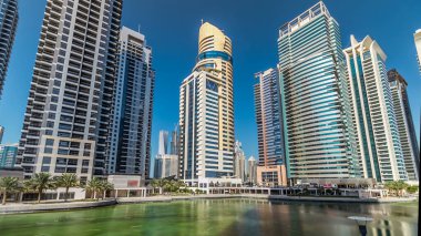 Rıhtımdaki palmiyeli gökdelenlerin hızlandırılmış görüntüsü. Jumeirah Gölü Kuleleri 'nde camla kaplı yerleşim yerleri Dubai, BAE' deki suya yansıdı. Rıhtımdan görüntüle