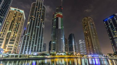 Rıhtımdaki ışıklandırılmış gökdelenlerin gece görüş açısını hızlandırın. Dubai, BAE 'deki Jumeirah Gölü Kuleleri' ndeki konut binaları. Rıhtımdan görüntüle