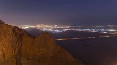 Jebel Hafeet 'teki kayalar ve yol trafiğiyle gündüz geçiş zamanı. Öncelikli olarak Al Ain 'in çevresinde yer alan dağ, şehir üzerinde etkileyici bir manzara sunuyor. Yukarıdan hava görünümü
