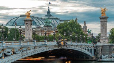 Paris 'teki Alexandre Köprüsü gece gündüz aydınlandı geçiş zamanı. Gün batımından sonra Grand Palais 'de. Trafik sıkışık. Paris, Fransa