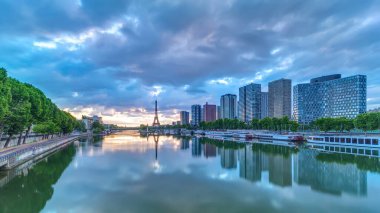 Eyfel Kulesi, Seine Nehri 'nde ve Fransa' nın Paris şehrinde teknelerle gün doğumu zamanı. Mirabeau Köprüsü 'nden gökyüzü dramatik bir şekilde görünüyor. Modern binalar ve yol trafiği. Özgürlük Anıtı