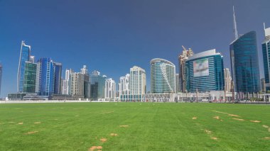 Panoramic timelapse hyperlapse view of business bay and downtown area of Dubai. Modern skyscrapers, green grass and blue sky clipart