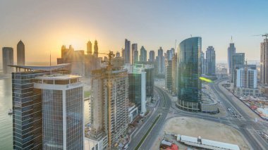 Dubai iş hangarı kuleleri, gün batımında hava saatinde. Bazı gökdelenlerin panoramik çatısı ve inşaat halindeki yeni kulelerin manzarası.