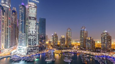 Dubai Marina gökdelenleri hava gününden geceye geçiş panoramik zaman çizelgesi lüks yatları ve marina gezinti güvertesi olan liman, Dubai, Birleşik Arap Emirlikleri. Aydınlatılmış kuleler ve yol trafiği