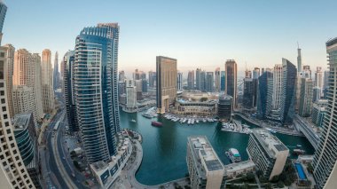 Dubai Marina 'nın gece gündüz aydınlanması. Hava geçiş panoramik zaman dilimi, BAE. Modern gökdelenler ve konut binaları. Yapay kanal şehrindeki alışveriş merkezinin yakınındaki yatlar ve tekneler.