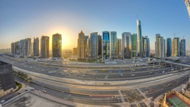 Jumeirah göl kulelerinin gökdelenleri gün doğumunda Şeyh zayed yolunda ve metro hattında trafik varken. Dubai marinasından çatı manzarası