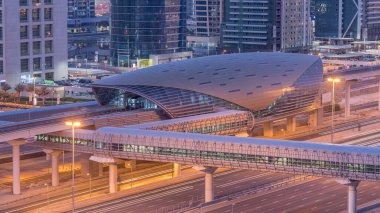 Jumeirah göl kulelerinin hava görüntüsü. Gece gündüz yaya köprüsü geçiş zamanı. Şeyh zayed yolunda ve metro hattında trafik var. Dubai marinasından güneş doğmadan önce çatı manzarası