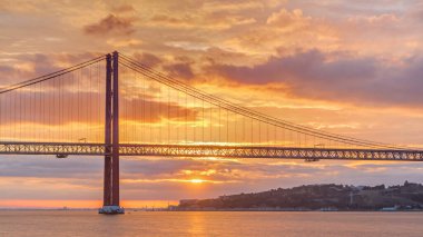 Lisbon city sunrise with April 25 bridge timelapse, River and waterfront early morning. Orange clouds on the sky