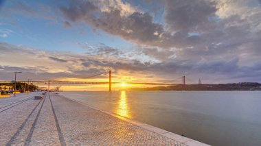 Lisbon city sunrise with April 25 bridge panoramic timelapse, River and waterfront early morning. Colorful cloudy sky