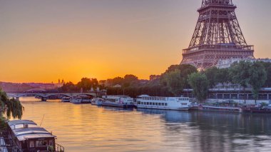 Eiffel Tower and the Seine river at Sunrise timelapse, Paris, France. Morning view from Bir-Hakeim bridge with reflections on water and orange sky clipart