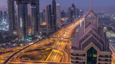 Dubai şehir merkezi silueti en yüksek gökdelenler ve karayolu kavşak gece gündüz geçiş timelapse üzerinde en işlek trafik ile. Yukarıdan havadan görünüm